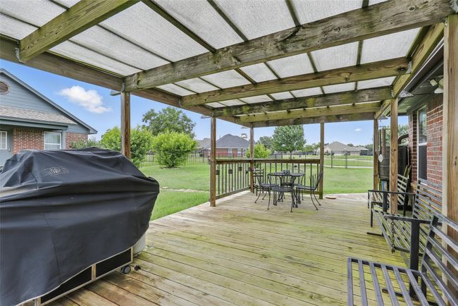 Wooden terrace with area for grilling, outdoor dining space, a fenced backyard, and a residential view | Image 31