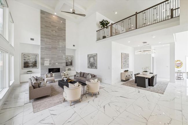 Modern design meets grandeur.. This impressive space features soaring high ceilings that create an open, airy ambiance, enhancing the room’s spacious feel. The architectural brilliance of this room is showcased by its visibility of the second floor, offering a seamless flow and a sense of connectivity throughout the home. Anchored by a sleek, contemporary fireplace, this space is perfect for cozy evenings and lively gatherings alike. | Image 10
