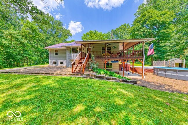 rear view of house featuring stairs, ceiling fan, a yard, a wooden deck, and an outdoor pool | Image 67