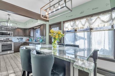 Kitchen with dark brown cabinetry, light stone countertops, sink, decorative backsplash, and appliances with stainless steel finishes | Image 3