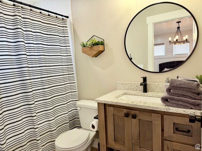 Full bath with vanity, a shower with shower curtain, toilet, and an inviting chandelier | Image 27