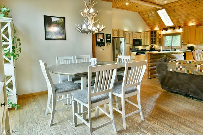 Dining room featuring wood ceiling, high vaulted ceiling, light wood finished floors, a chandelier, and baseboards | Image 11