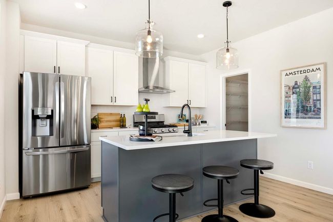 The kitchen features a striking contrast between a sleek gray island and crisp white perimeter cabinets, creating a modern and sophisticated look. Photos are from previously built home; options and features will vary. | Image 12
