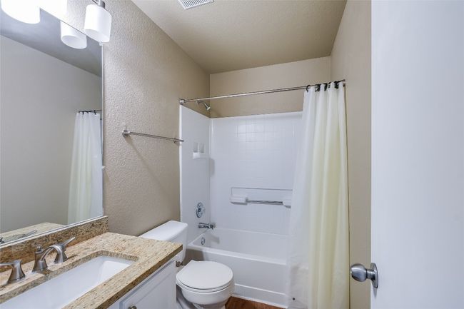Bathroom featuring vanity, toilet, shower / bath combo with shower curtain, and a textured wall | Image 16