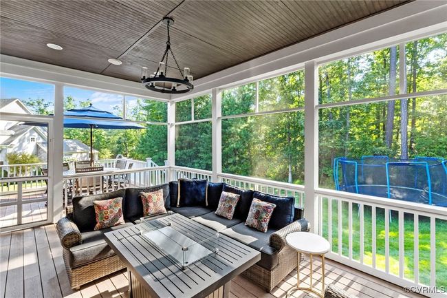 Wooden deck with an outdoor hangout area, a ceiling fan, view of scattered trees, and a trampoline | Image 44