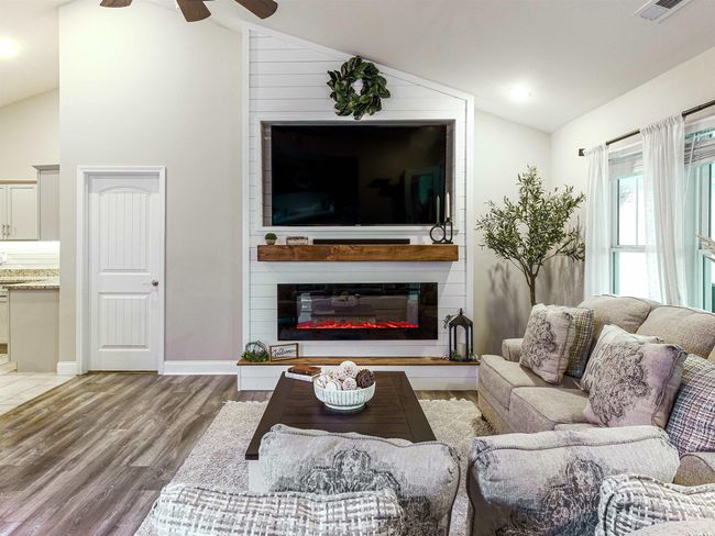 Living room featuring a fireplace, hardwood / wood-style floors, vaulted ceiling, and ceiling fan | Image 4