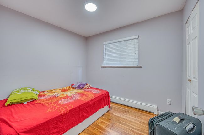 Bedroom with baseboard heating, wood finished floors, and a closet | Image 21