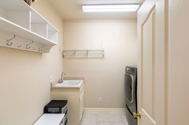 Laundry area featuring washer / dryer, cabinet space, light tile patterned floors, and baseboards | Image 25
