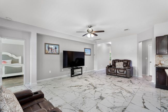 Living area featuring a ceiling fan, light marble finish floors, and baseboards | Image 6