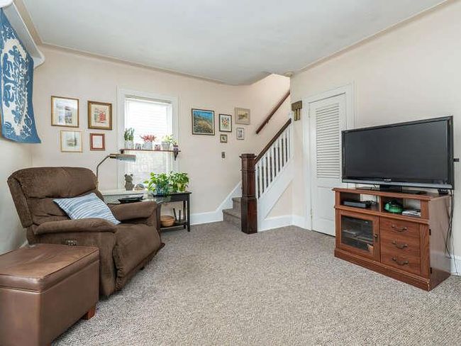Carpeted living area featuring baseboards and stairway | Image 4
