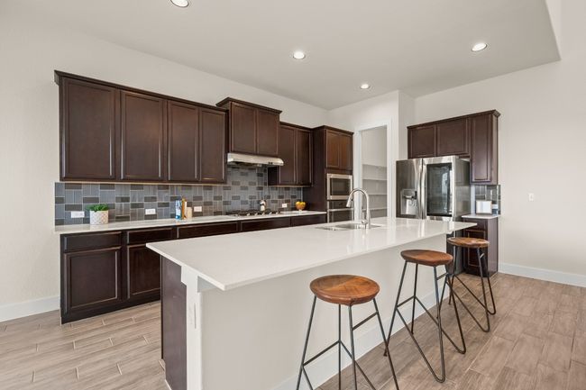 Kitchen with under cabinet range hood, stainless steel appliances, light wood-style floors, tasteful backsplash, and recessed lighting | Image 17
