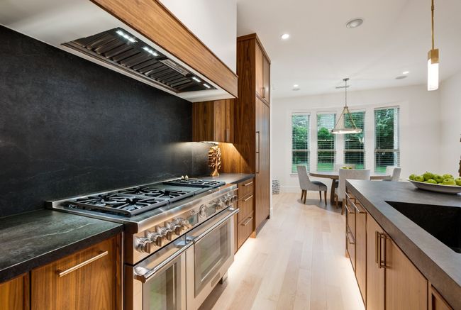 Kitchen with double oven range, dark countertops, light wood finished floors, custom exhaust hood, and recessed lighting | Image 10