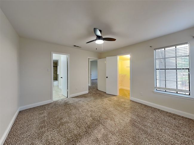 Unfurnished bedroom with a spacious closet, visible vents, light carpet, baseboards, and ceiling fan | Image 18