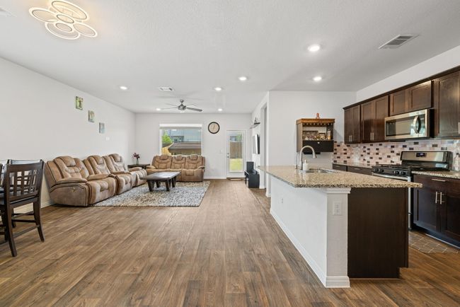 Kitchen featuring appliances with stainless steel finishes, a sink, open floor plan, dark brown cabinetry, and dark wood-style floors | Image 4