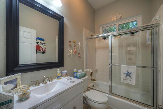 Full bath featuring bath / shower combo with glass door, vanity, and toilet | Image 27