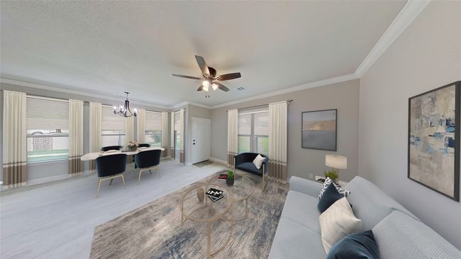 Virtually Staged. Living area featuring light wood-style flooring, visible vents, baseboards, and crown molding | Image 7