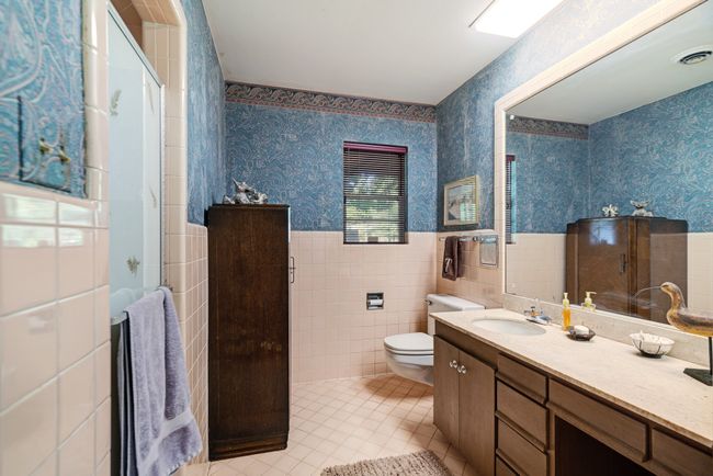 Full bath featuring tile patterned flooring, tile walls, wainscoting, wallpapered walls, and vanity | Image 22