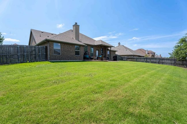 Back of house featuring brick siding, a fenced backyard, a chimney, a patio, and a shingled roof | Image 28