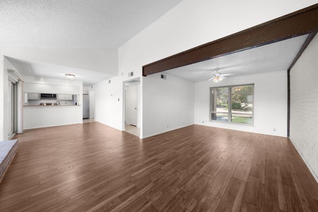 View of large L-shaped living and dining rooms with fireplace with long hearth just visible to the left. This space is large enough to create three separate living and work areas, as needed. | Image 9