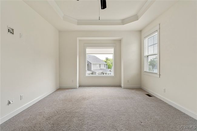 Spare room featuring ornamental molding, a tray ceiling, light carpet, and a ceiling fan | Image 28