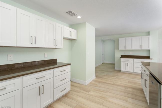 Kitchen with baseboards, arched walkways, light wood-type flooring, white cabinetry, and visible vents | Image 8