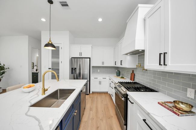 The kitchen features a pot filler, sleek quartz counters, recessed lighting, and tile backsplash. | Image 9