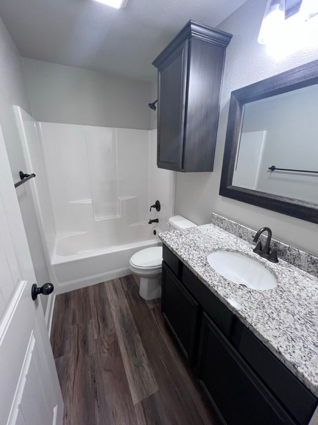 Full bath with vanity, wood finished floors, shower / washtub combination, and toilet | Image 33