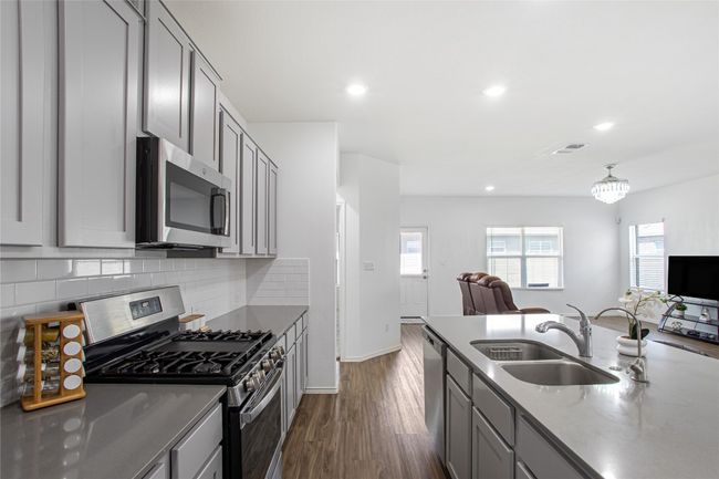 Kitchen featuring stainless steel appliances, gray cabinetry, a sink, and open floor plan | Image 14