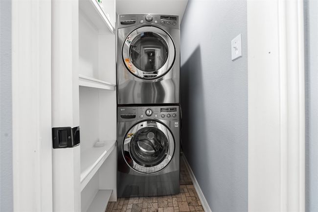 Washroom featuring stacked washer / dryer and stone finish flooring | Image 18