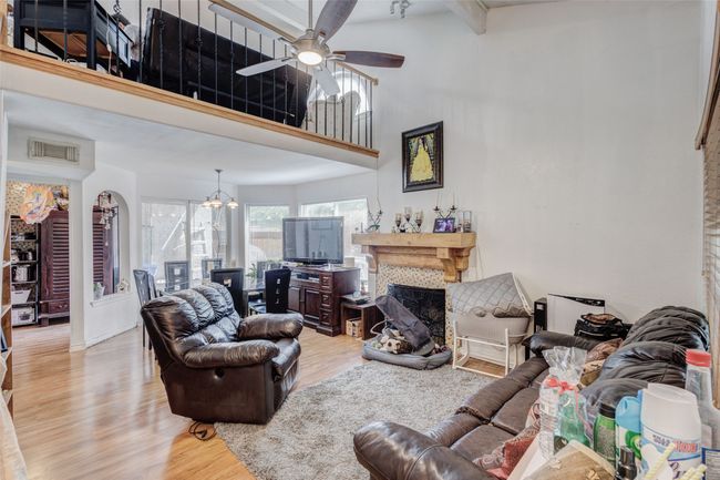 Living room featuring a fireplace, visible vents, light wood-style floors, and ceiling fan with notable chandelier | Image 16