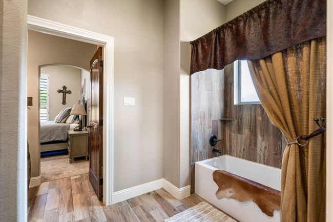 Bathroom featuring healthy amount of natural light, wood finished floors, bathing tub / shower combination, and connected bathroom | Image 26