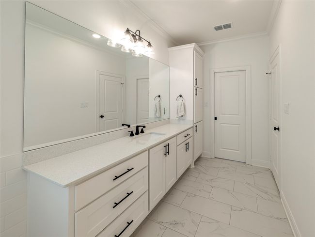 Bathroom featuring vanity, marble look tile flooring, and crown molding | Image 23