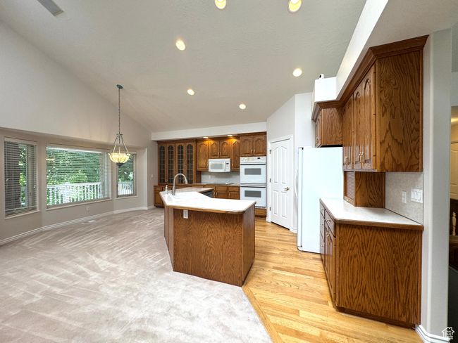 Vaulted kitchen with dual ovens and built in glass cabinets and hardwood floor. | Image 11