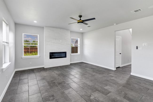 Unfurnished living room featuring ceiling fan, a fireplace, recessed lighting, baseboards, and heating unit | Image 10