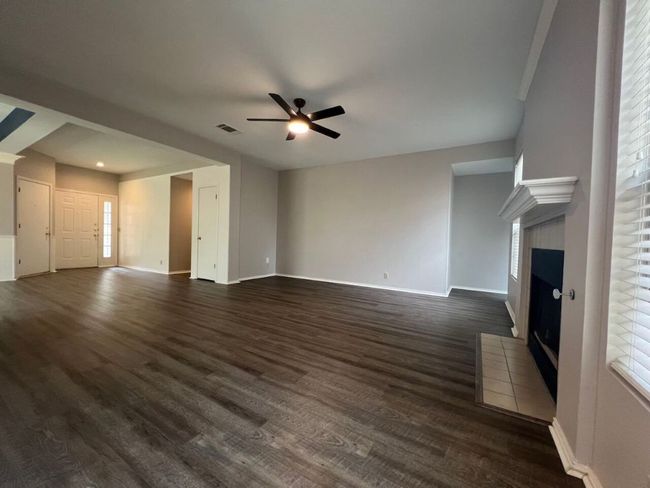 Unfurnished living room featuring a fireplace, dark wood-style floors, and a ceiling fan | Image 15