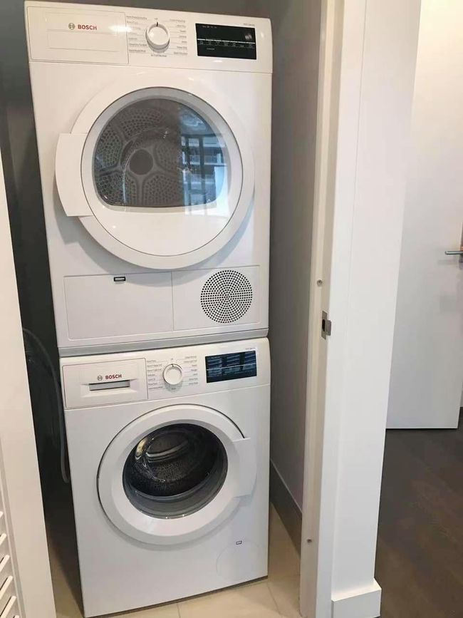 Washroom with stacked washing machine and dryer and tile patterned flooring | Image 8