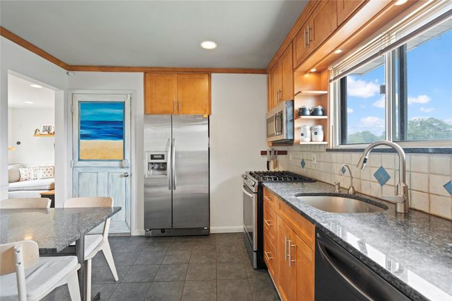 Kitchen featuring stainless steel appliances, tasteful backsplash, dark tile patterned flooring, recessed lighting, and dark stone countertops | Image 15