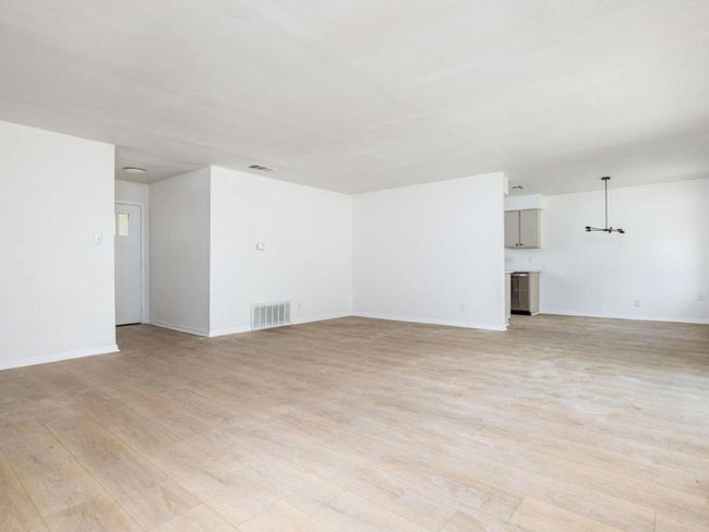Unfurnished living room with light wood finished floors, baseboards, and a chandelier | Image 5