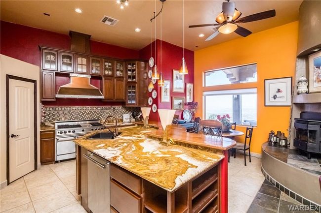 Kitchen with ventilation hood, appliances with stainless steel finishes, a wood stove, light tile patterned floors, and recessed lighting | Image 33