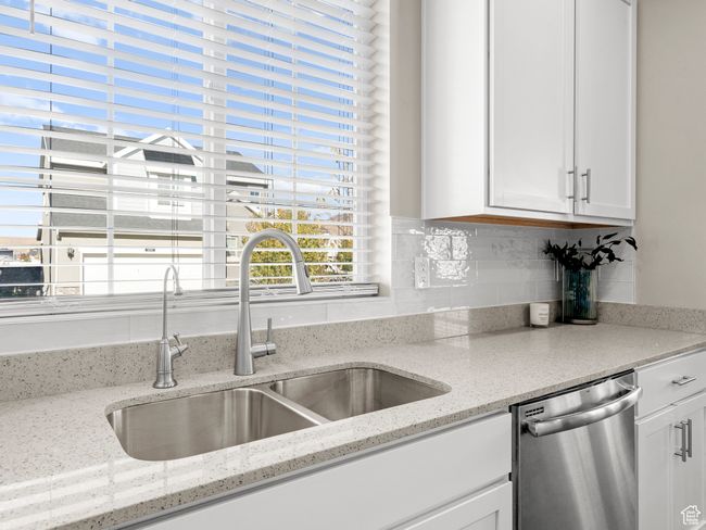 Kitchen featuring dishwasher, decorative backsplash, white cabinetry, and light stone countertops | Image 13