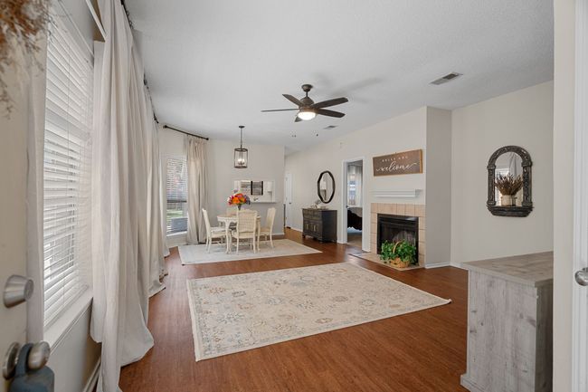 Living area with ceiling fan, wood finished floors, and a fireplace | Image 5