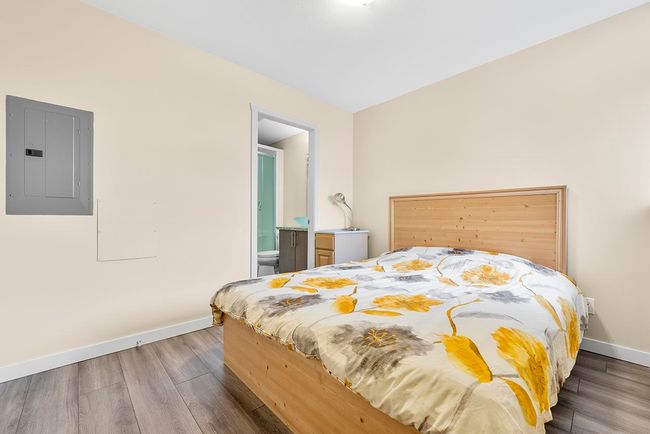 Bedroom featuring ensuite bath, electric panel, wood finished floors, and baseboards | Image 12