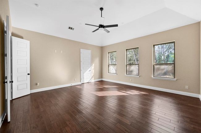 Unfurnished room featuring dark wood-style floors, visible vents, a ceiling fan, vaulted ceiling, and baseboards | Image 31