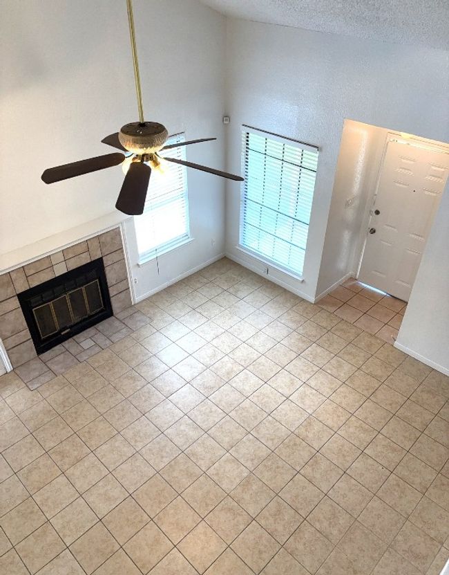 Unfurnished living room featuring light tile patterned floors, ceiling fan, a textured ceiling, and a fireplace | Image 16