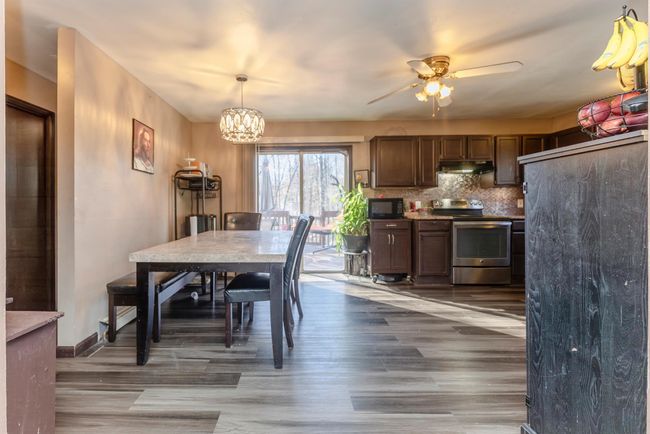 Dining area featuring ceiling fan with notable chandelier, wood finished floors, and baseboards | Image 6