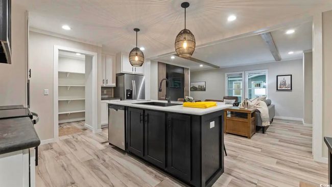 Kitchen featuring stainless steel appliances, a sink, dark cabinets, white cabinets, and light wood-style floors | Image 15