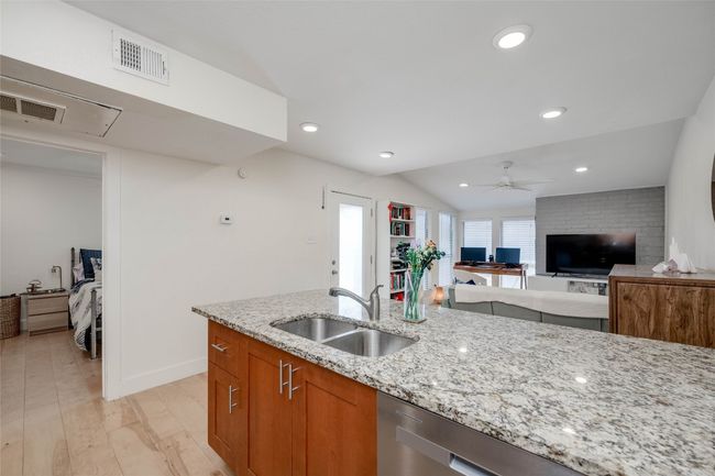 Kitchen featuring light stone countertops, brown cabinetry, dishwasher, lofted ceiling, and ceiling fan | Image 8