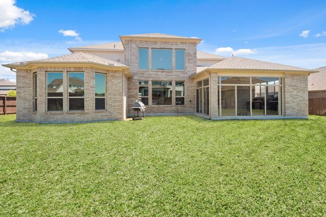 Rear view of house with brick siding, a yard, a sunroom, and fence | Image 33
