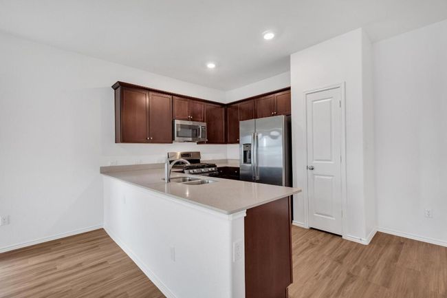 Kitchen with light wood-type flooring, light countertops, a peninsula, and stainless steel appliances | Image 5