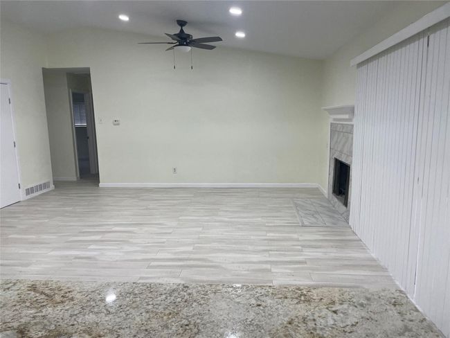 Unfurnished living room with a ceiling fan, light wood-type flooring, a tiled fireplace, recessed lighting, and lofted ceiling | Image 22